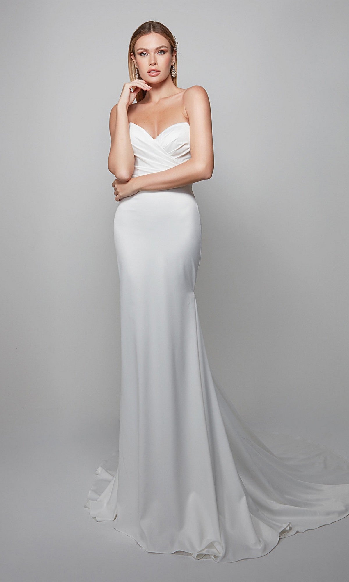 A woman models the Alyce 7056 long formal dress, featuring a strapless sweetheart neckline and flowing train, set against a plain light gray background.